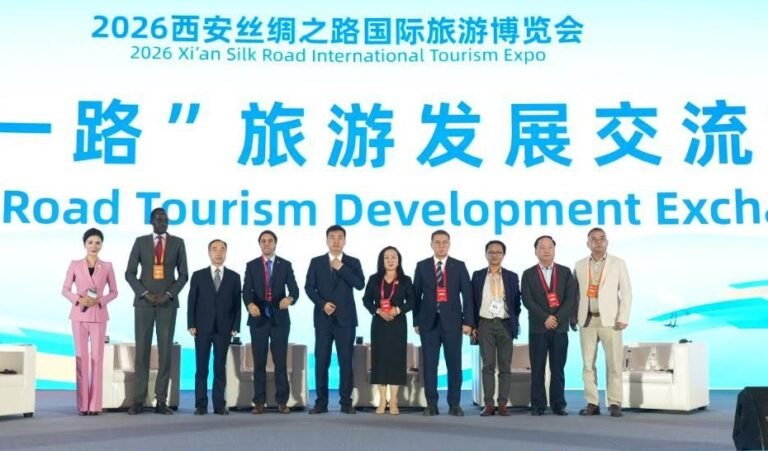 Group of professionals in business attire standing on a stage at the 2026 Xi’an Silk Road International Tourism Expo, in front of a large blue signage banner.