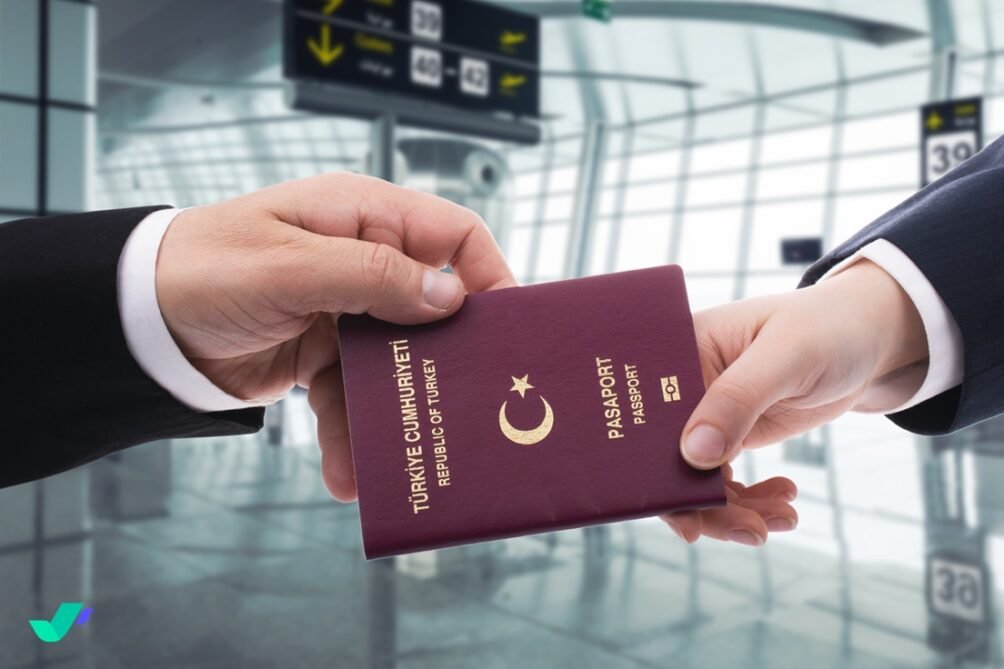 Two hands exchange a Turkish passport at an airport, indicating travel or border control.