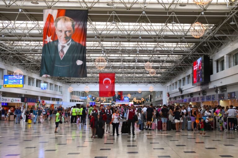 Busy airport terminal with travelers and Turkish flags hanging from the ceiling.
